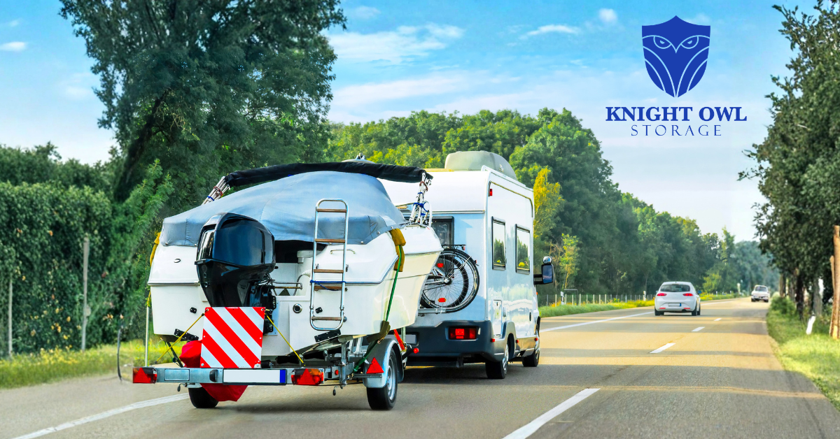 A motorhome towing a covered boat on a trailer down a highway under a clear blue sky